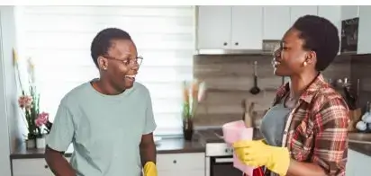 Two cheerful women cleaning the kitchen and smiling