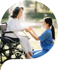 Elderly woman on wheelchair with caregiver.