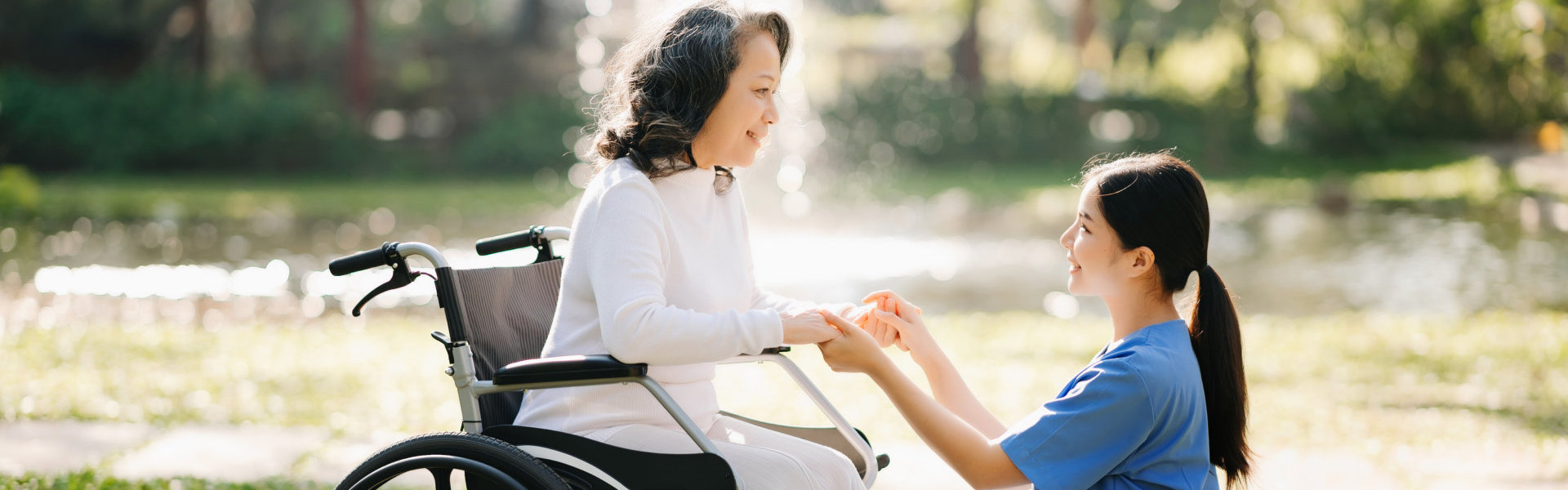 Elderly woman on wheelchair with caregiver.