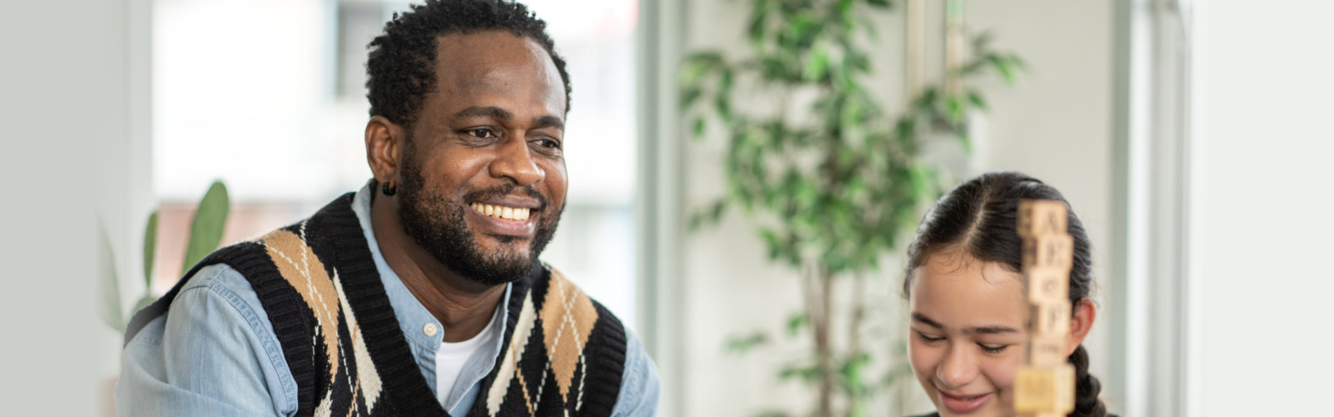 Smiling teacher watching student arranging wood toy in the classroom